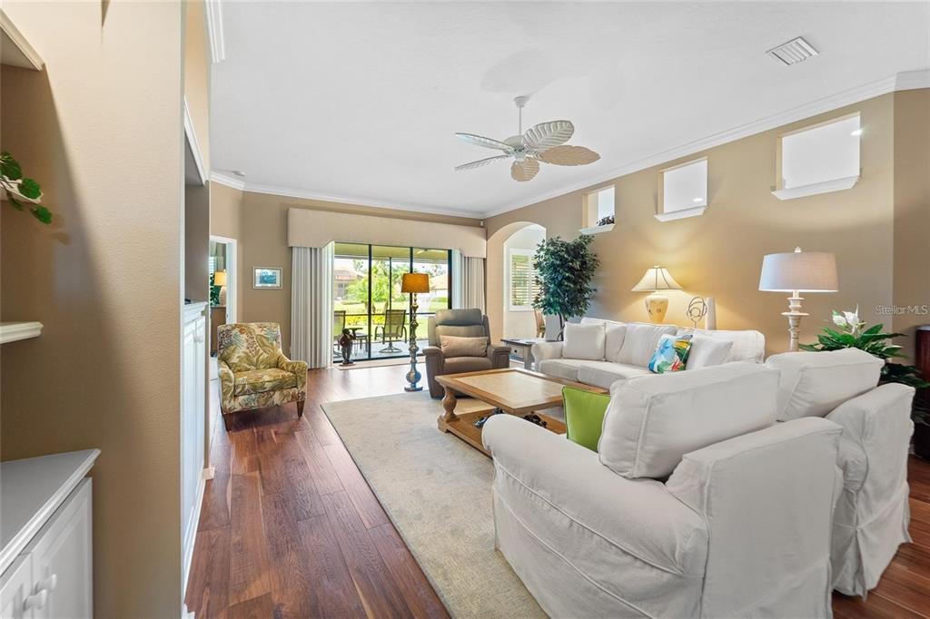 A living room with white sofas, a wooden coffee table, and hardwood floors — 5175 CANTABRIA CREST, SARASOTA, FL