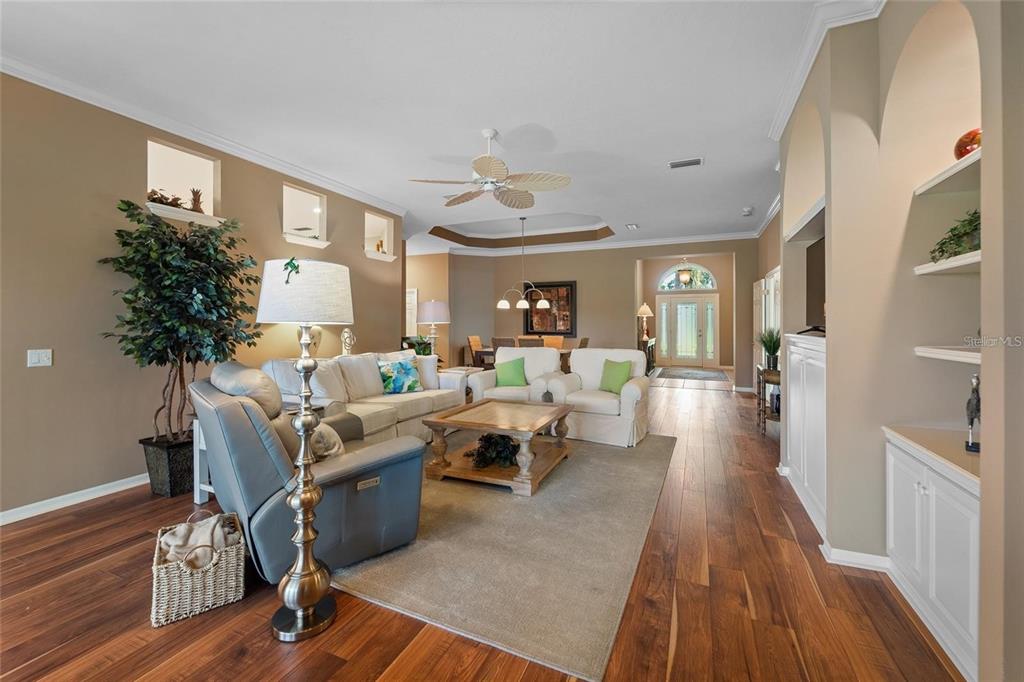 A living room features hardwood floors, a neutral sofa set, and built-in shelving — 5175 CANTABRIA CREST, SARASOTA, FL
