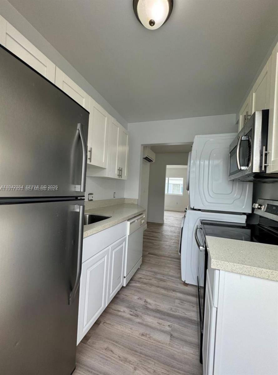 An empty bedroom features light gray walls, wood-look flooring, and a window overlooking a roof — 1248 Marseille Dr # 4, Miami Beach FL 33141, MIAMI BEACH, FL