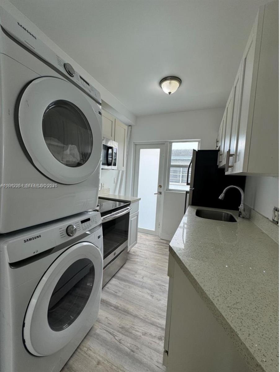 A galley kitchen features white cabinets, stainless steel appliances, and light-colored countertops — 1248 Marseille Dr # 4, Miami Beach FL 33141, MIAMI BEACH, FL