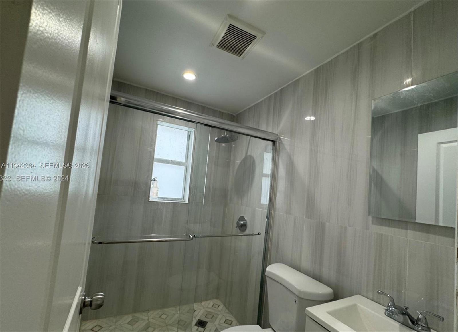 A kitchen featuring a stacked washer and dryer, white cabinets, and light-colored countertops — 1248 Marseille Dr # 4, Miami Beach FL 33141, MIAMI BEACH, FL