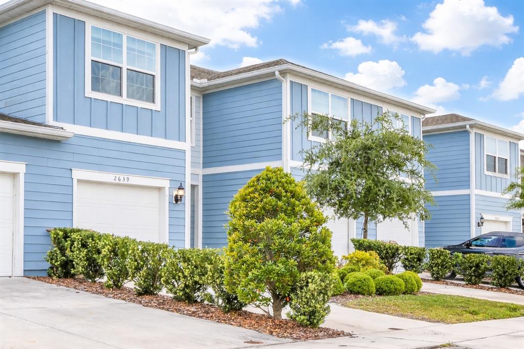 A row of blue two-story townhouses with attached garages and landscaped front yards — 2639 BUENA VIEW ROAD, KISSIMMEE, FL