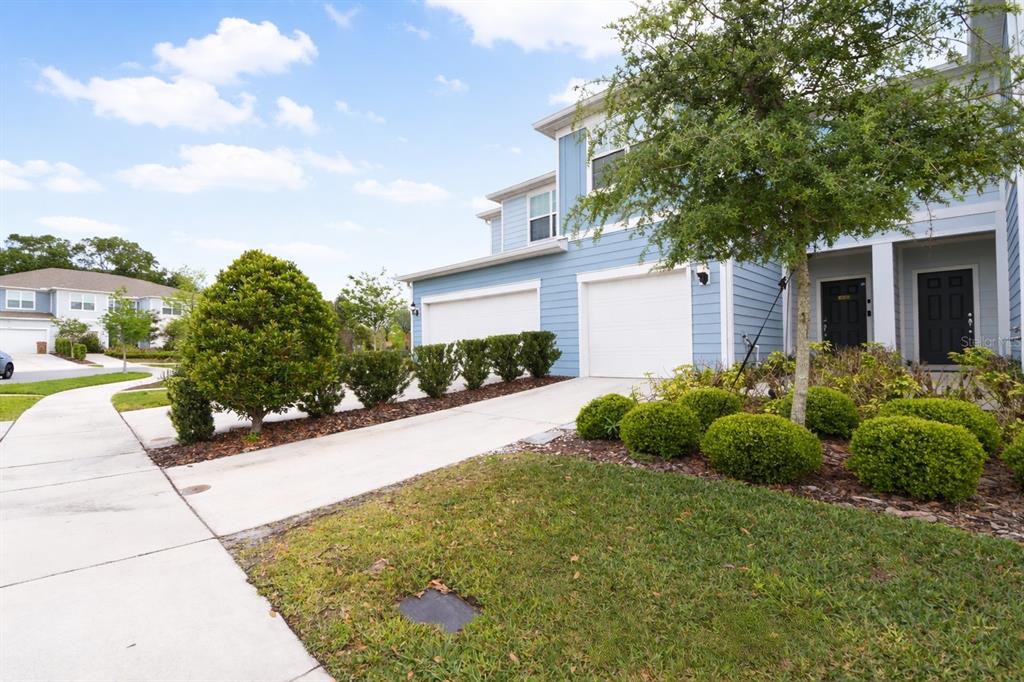 A blue two-story townhouse features a two-car garage, a concrete driveway, and landscaped front bushes — 2639 BUENA VIEW ROAD, KISSIMMEE, FL
