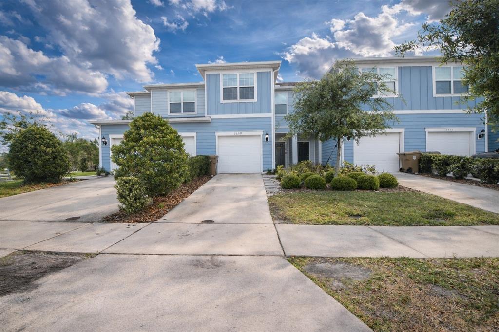 A blue multi-unit townhouse exterior features white garage doors and a concrete driveway — 2639 BUENA VIEW ROAD, KISSIMMEE, FL