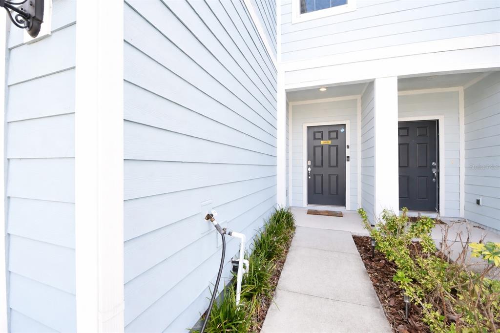 A concrete walkway leads to two dark gray front doors on a light blue house — 2639 BUENA VIEW ROAD, KISSIMMEE, FL
