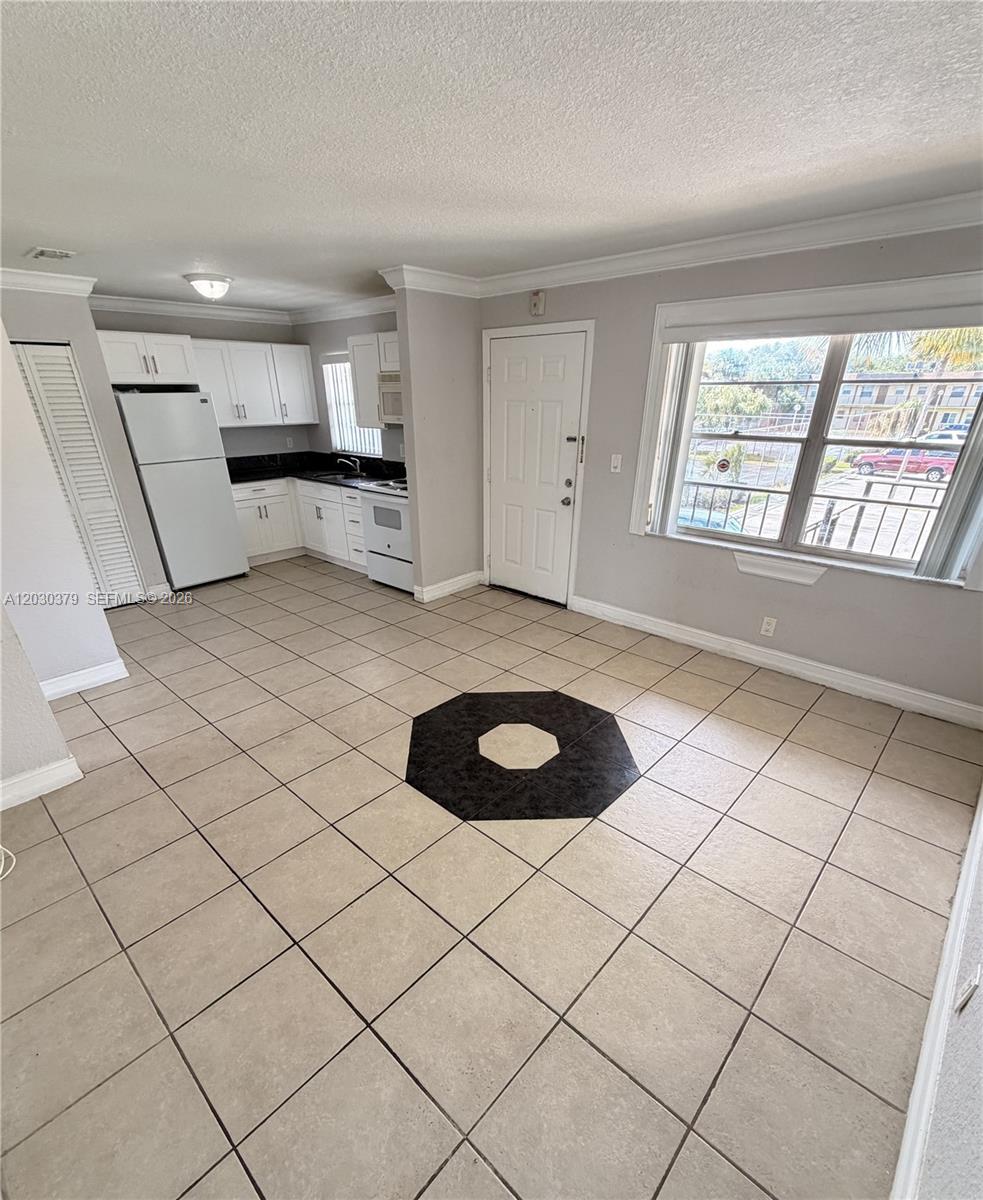 An open-concept kitchen and living area features white cabinets, tile flooring, and a large window — 412 Lakeside Dr # 223, Margate FL 33063, MARGATE, FL