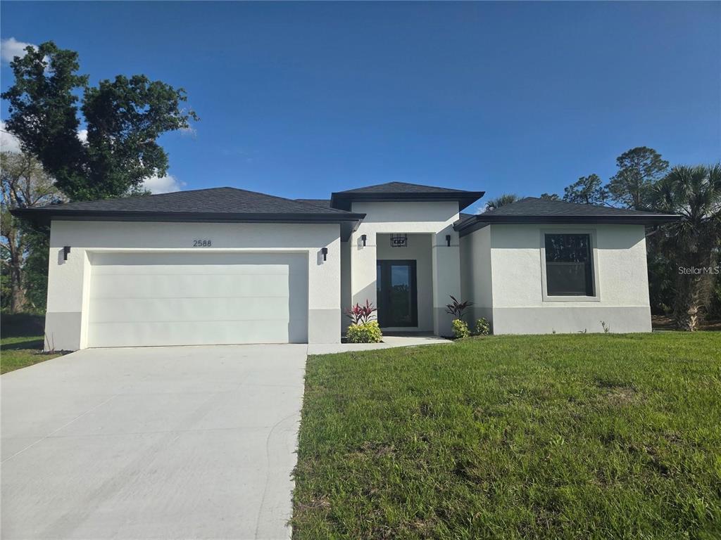 A single-story house with white stucco walls, a dark roof, and a two-car garage — 2074 RIBBON TERRACE, NORTH PORT, FL
