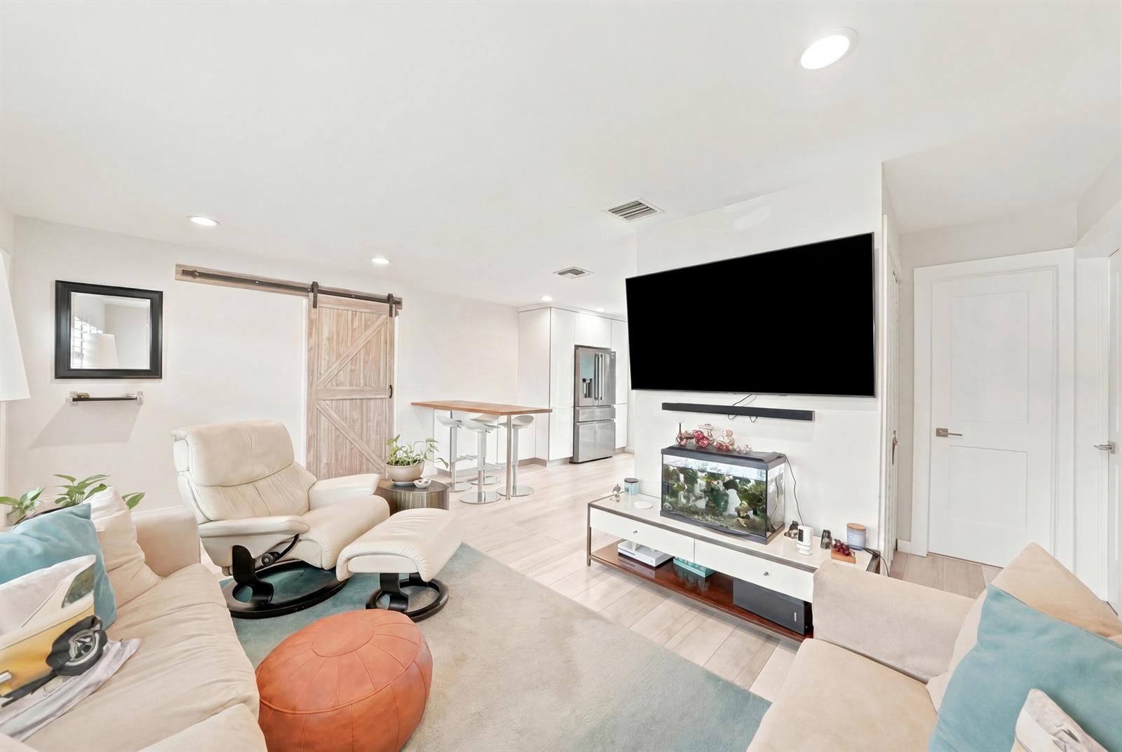 A living room features a large wall-mounted television, a fish tank, and a barn door — 3140 NE 12th Avenue, Pompano Beach FL 33064, POMPANO BEACH, FL