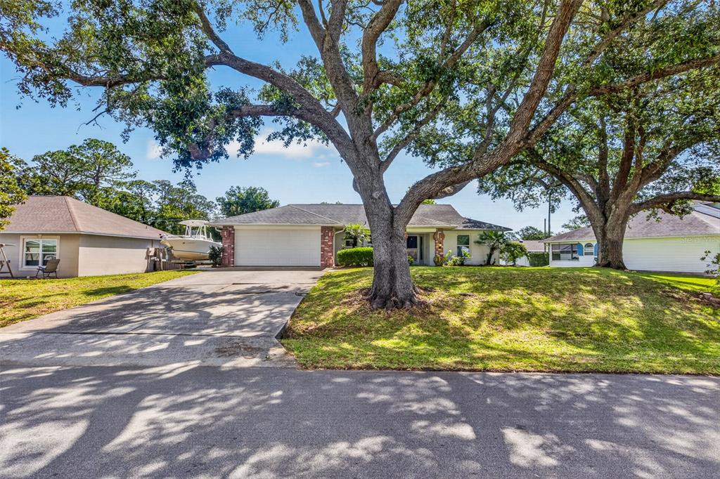 A single-story house with a two-car garage and large oak trees in the front yard — 2225 VISTA PALM DRIVE, EDGEWATER, FL