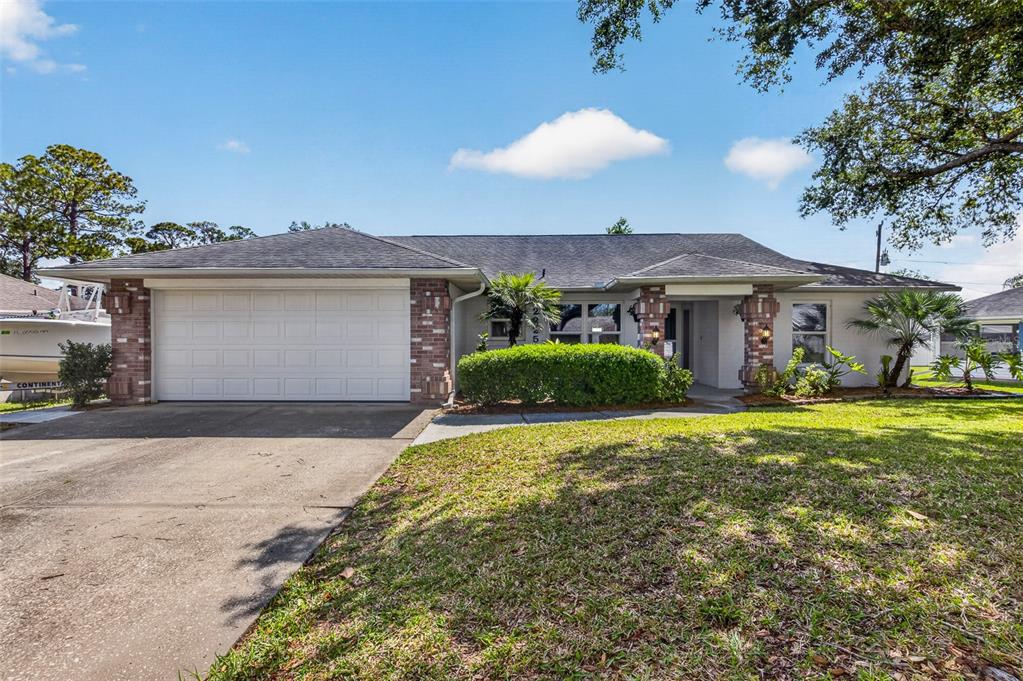 A single-story house with a white garage, brick accents, and a landscaped front yard — 2225 VISTA PALM DRIVE, EDGEWATER, FL