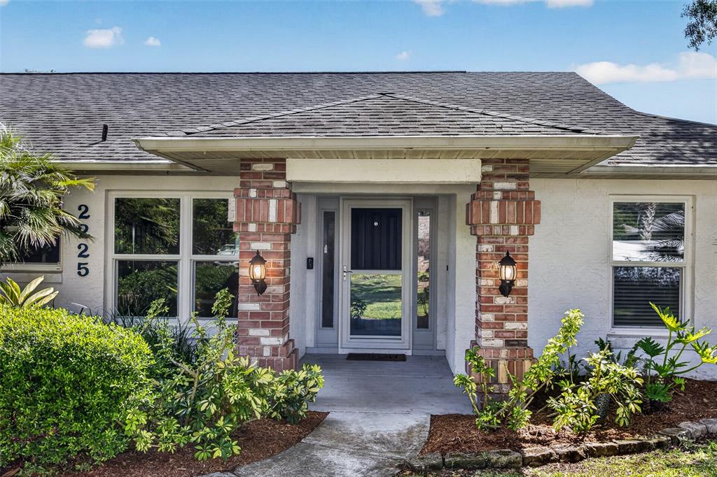 The exterior of a single-story house features a brick-columned entryway and a front door — 2225 VISTA PALM DRIVE, EDGEWATER, FL