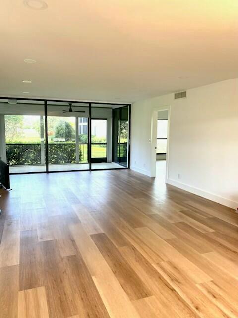 An empty room with light wood flooring, recessed lighting, and large glass sliding doors — 10 SE Turtle Creek Drive Unit B, Tequesta FL 33469, TEQUESTA, FL