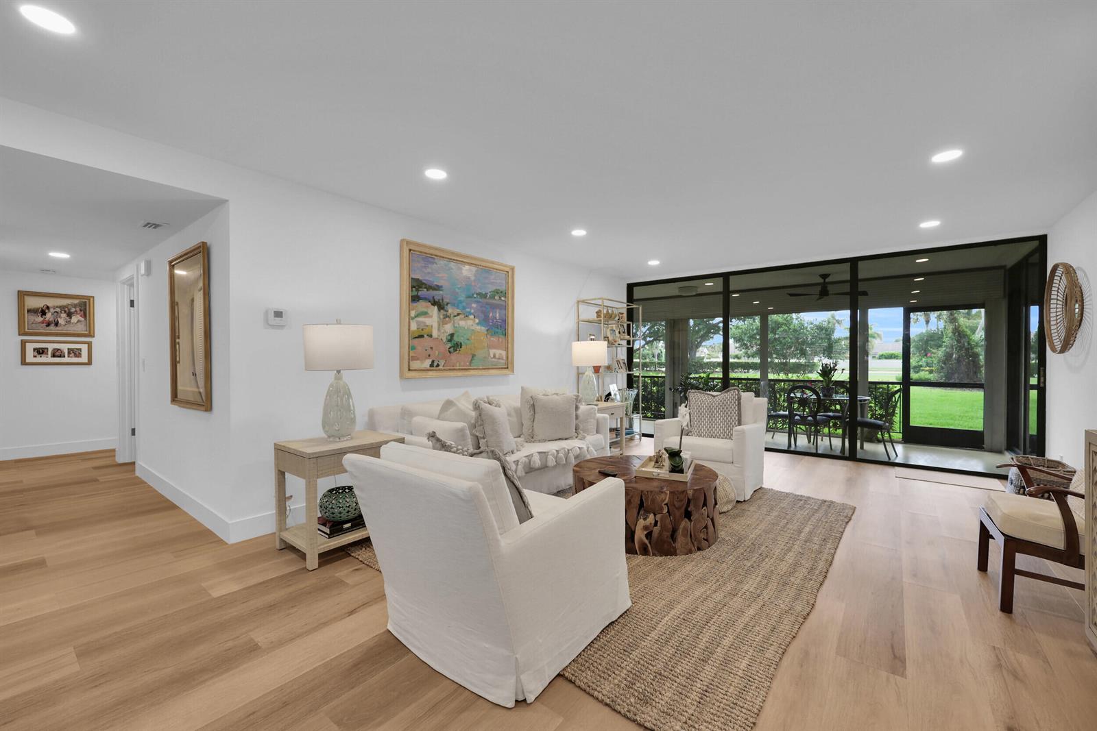 A bright living room features light wood flooring, white furniture, and a large screened-in patio — 10 SE Turtle Creek Drive Unit B, Tequesta FL 33469, TEQUESTA, FL