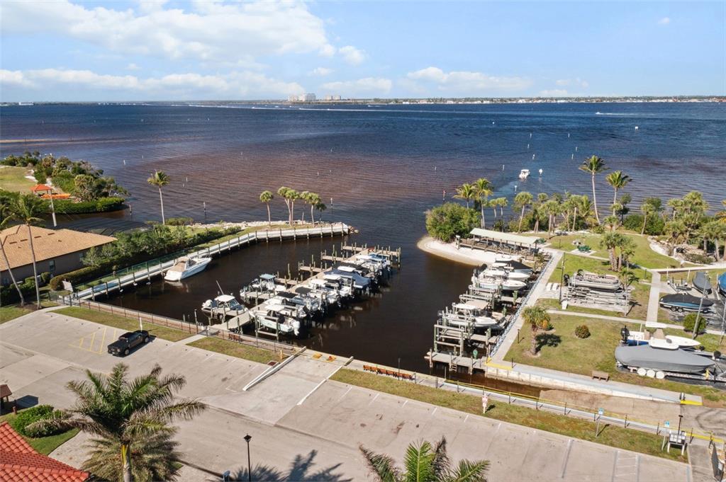 An aerial view shows a boat basin with multiple slips and docks along a waterfront — 14815 LAGUNA DRIVE UNIT 702, FORT MYERS, FL