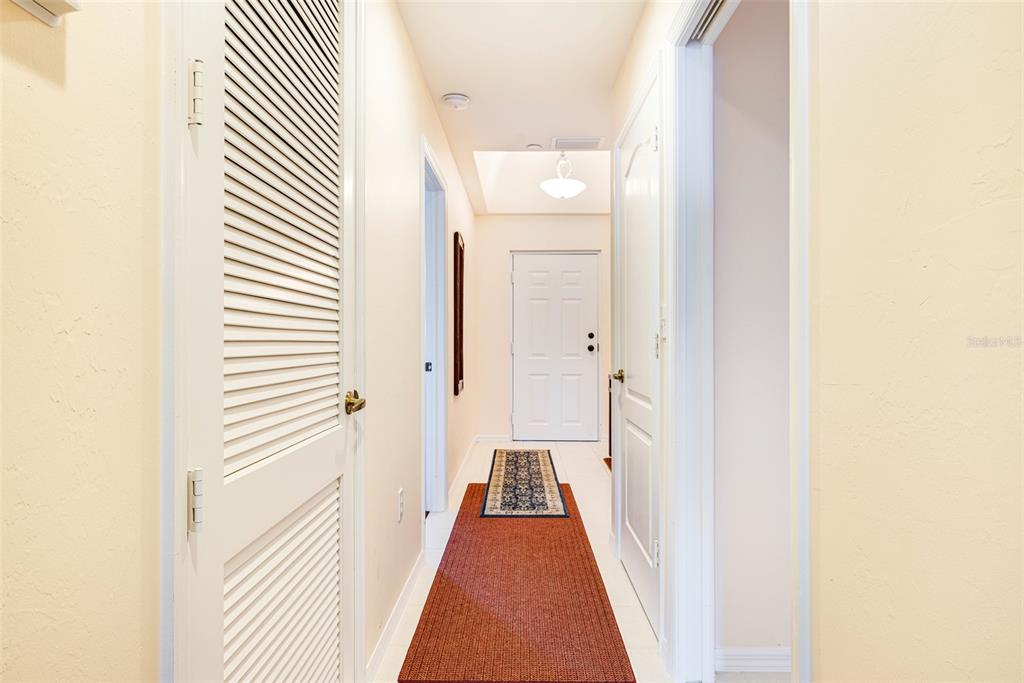 A hallway with light walls, white doors, and a long red runner rug on the floor — 14815 LAGUNA DRIVE UNIT 702, FORT MYERS, FL