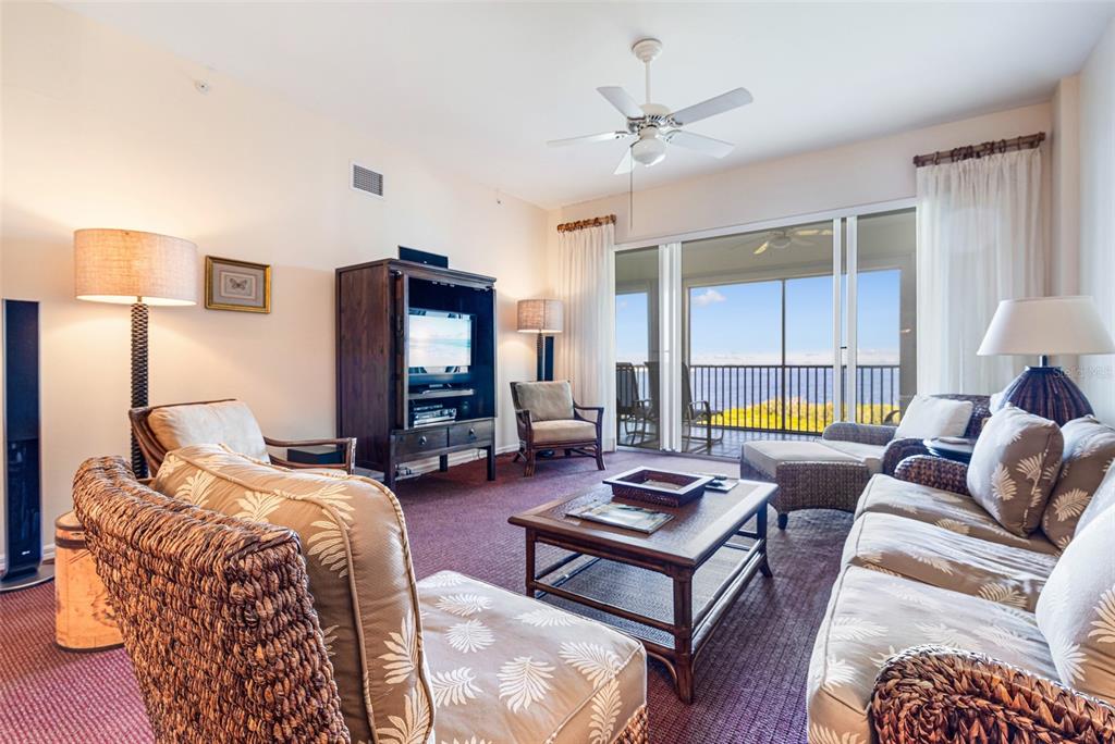 A living room with wicker furniture, a television cabinet, and a balcony overlooking the ocean — 14815 LAGUNA DRIVE UNIT 702, FORT MYERS, FL