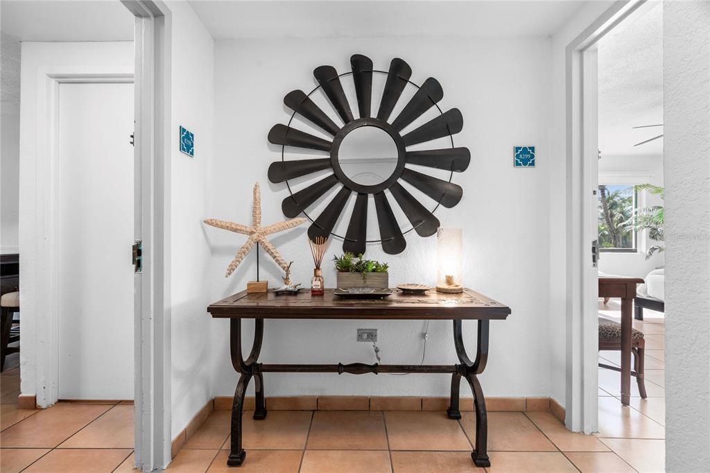 A wooden console table sits against a white wall beneath a large circular metal mirror — 6100 RIO MAR UNIT 829899, RIO GRANDE, PR