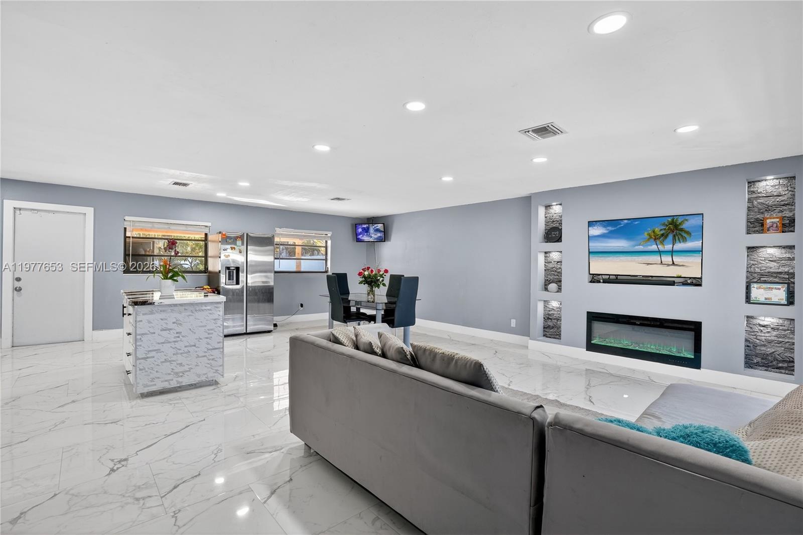 A living room and dining area feature marble-look tile floors, a fireplace, and recessed shelving — 1318 13th St, West Palm Beach FL 33401, WEST PALM BEACH, FL