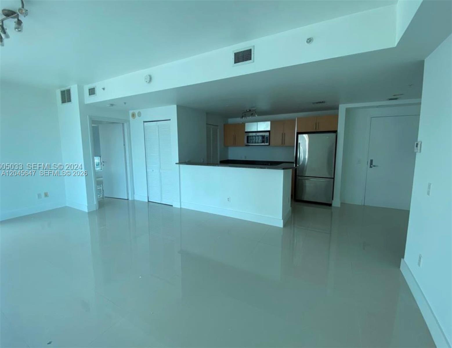 An open-concept living area features a kitchen with light wood cabinets and stainless steel appliances — 300 S Biscayne Blvd # 2302, Miami FL 33131, MIAMI, FL