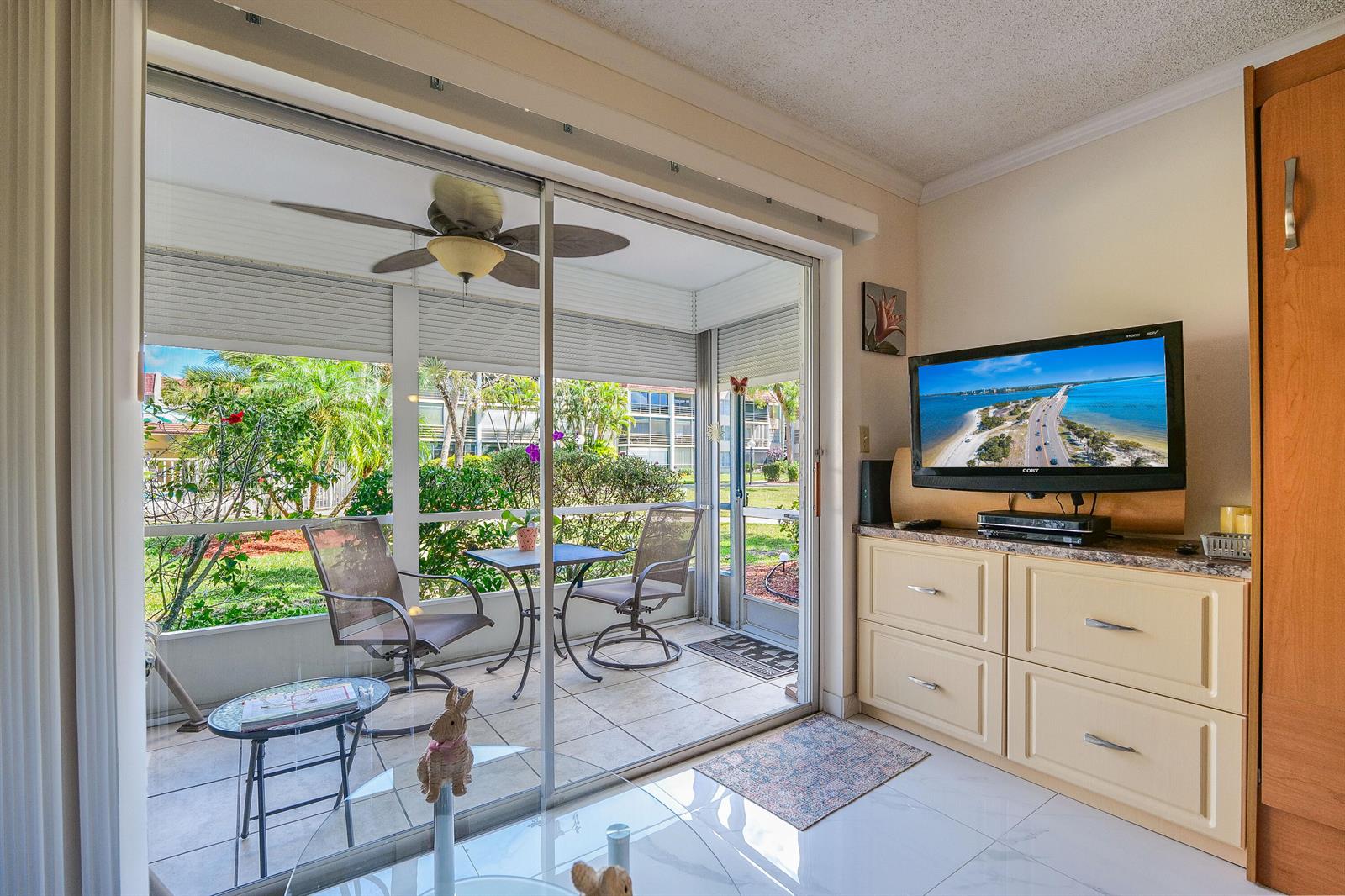 A living room with a television console leads to a screened-in patio with outdoor seating — 3531 Inverrary Drive # 105, Lauderhill FL 33319, LAUDERHILL, FL