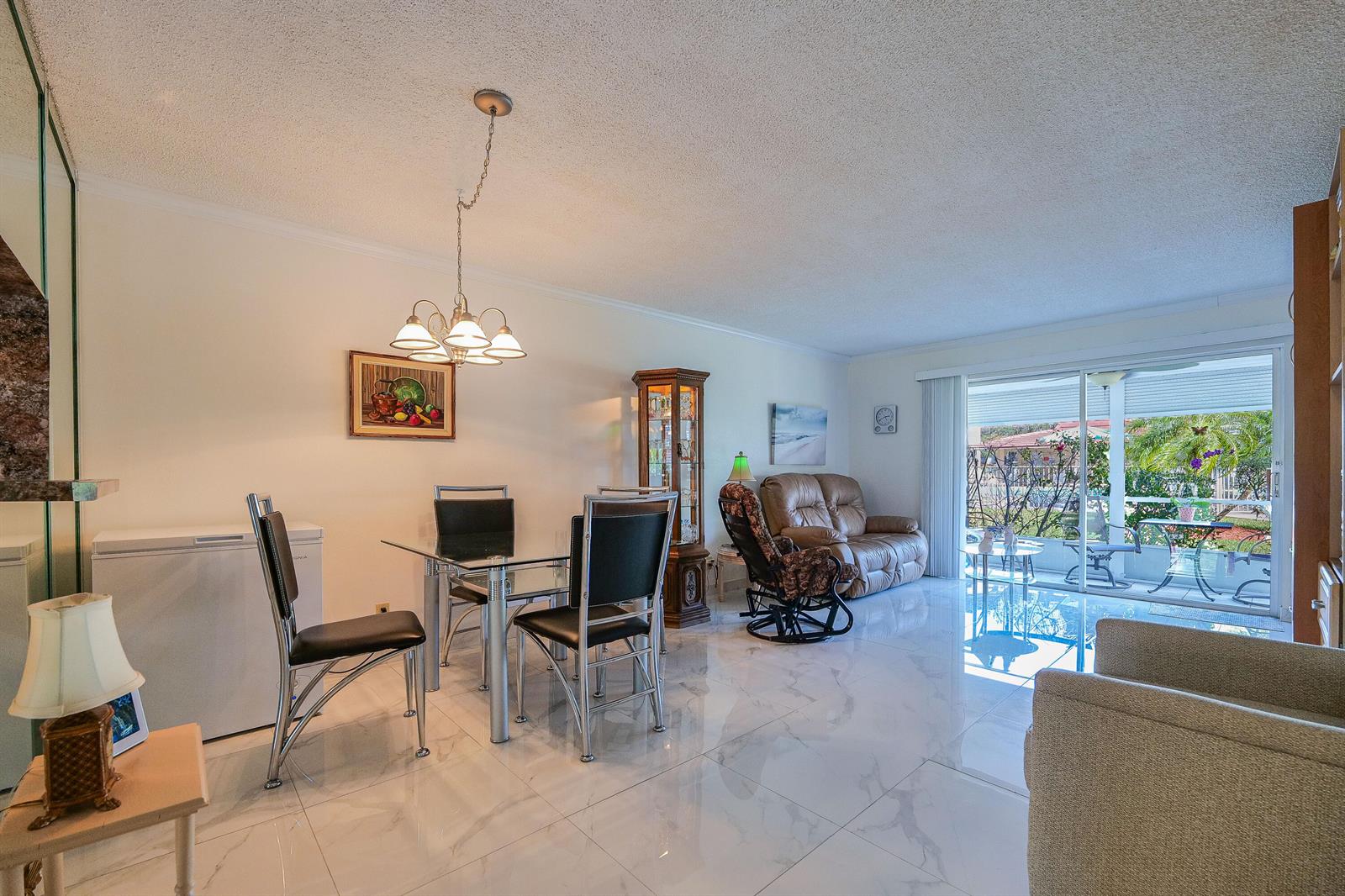 A dining and living area features white marble-look tile flooring and a glass-top dining table — 3531 Inverrary Drive # 105, Lauderhill FL 33319, LAUDERHILL, FL