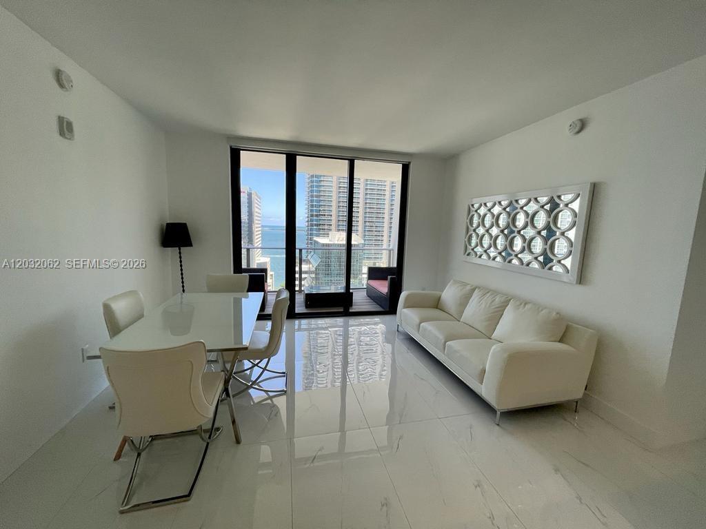A bright dining and living area features white tile floors, modern furniture, and a balcony — 1010 Brickell Ave # 2704, Miami FL 33131, MIAMI, FL