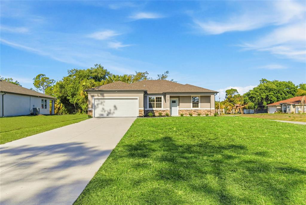 A single-story house with a two-car garage, stone accents, and a large front lawn — 5101 S SAN MATEO DRIVE, NORTH PORT, FL