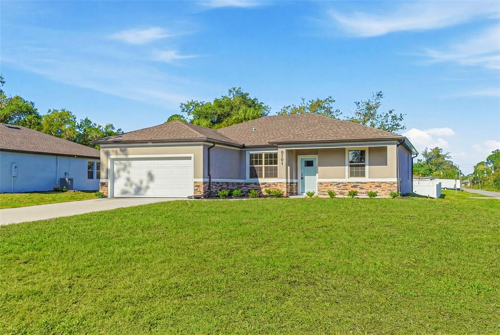A single-story house with a white garage, stone veneer siding, and a light blue door — 5101 S SAN MATEO DRIVE, NORTH PORT, FL
