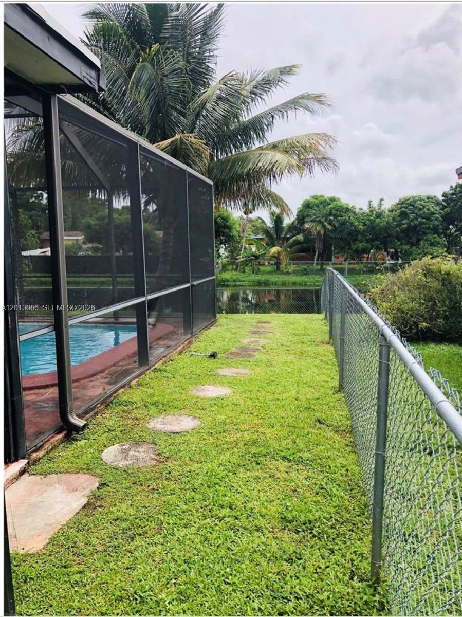 A grassy side yard features a swimming pool enclosure, a chain-link fence, and stepping stones — 2160 NW 82nd Ter, Sunrise FL 33322, SUNRISE, FL