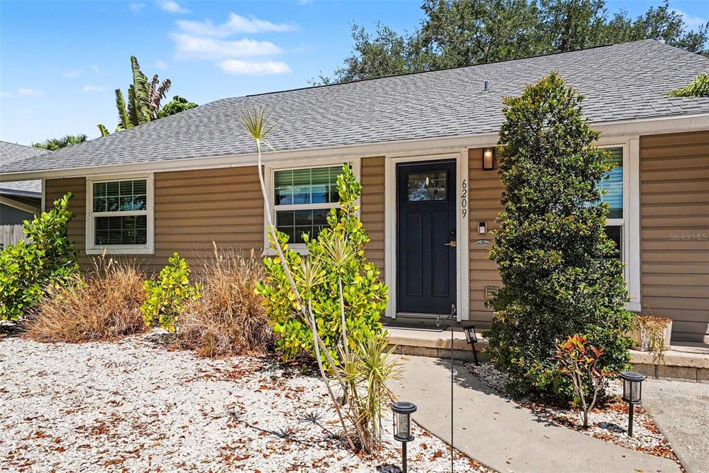 A one-story house with tan horizontal siding, a dark blue front door, and gravel landscaping — 6209 INTERBAY BOULEVARD, TAMPA, FL