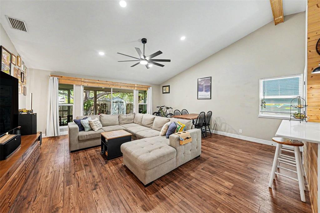 A living room features a sectional sofa, wood flooring, a vaulted ceiling, and dining area — 6209 INTERBAY BOULEVARD, TAMPA, FL