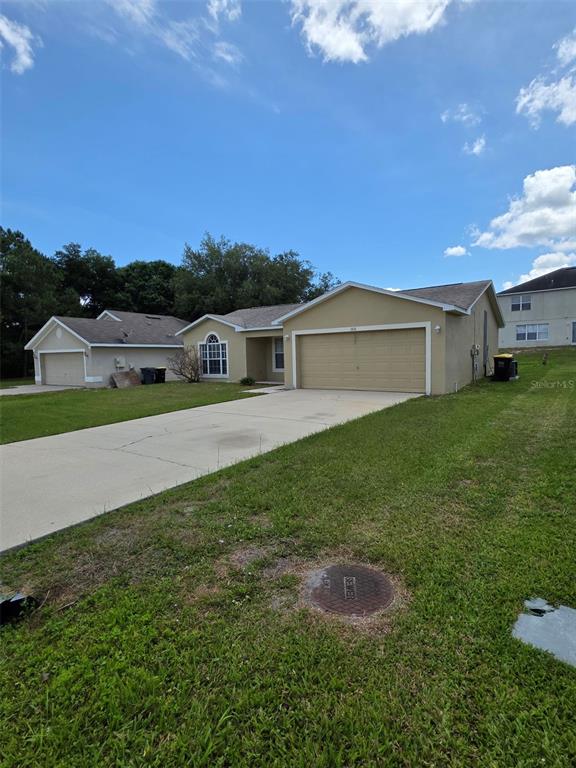 A tan, single-story suburban house with a two-car garage and a concrete driveway — 106 HERRING LANE, POINCIANA, FL