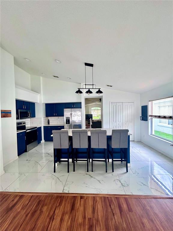 A kitchen features blue cabinets, a central island with four chairs, and white tiled floors — 1061 PORTMOOR WAY, WINTER GARDEN, FL