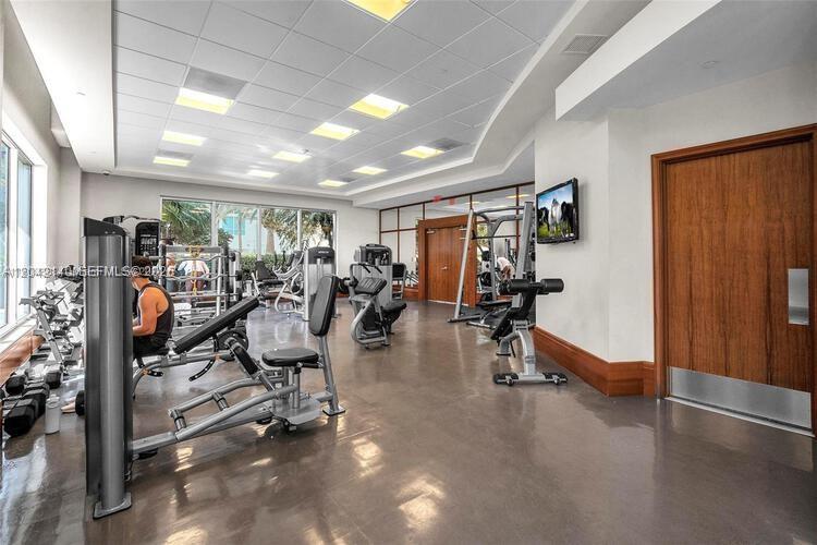 A bright, modern fitness center features various exercise machines, a drop ceiling, and wood doors — 1050 Brickell Ave # 416, Miami FL 33131, MIAMI, FL