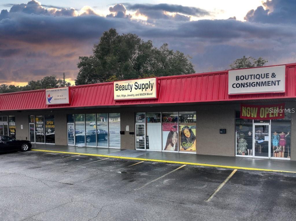 A commercial strip mall building with a red roof and several storefronts under a cloudy sky — 3410 NE JACKSONVILLE ROAD, OCALA, FL