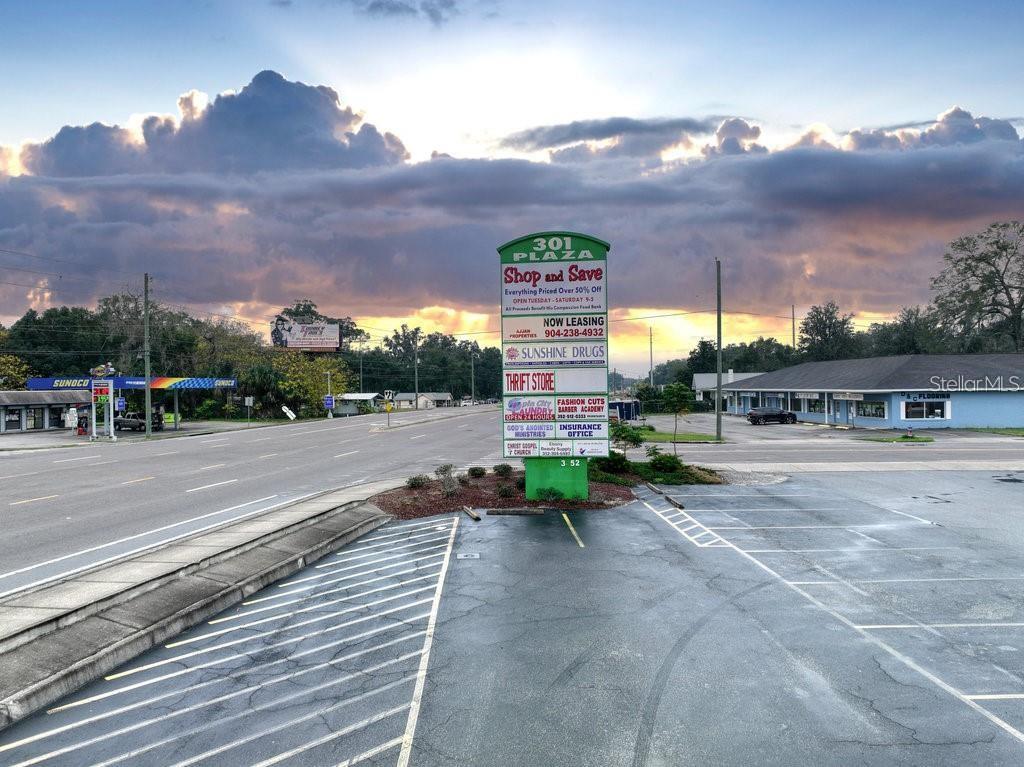 A parking lot sits in front of a commercial plaza sign under a cloudy sky — 3410 NE JACKSONVILLE ROAD, OCALA, FL
