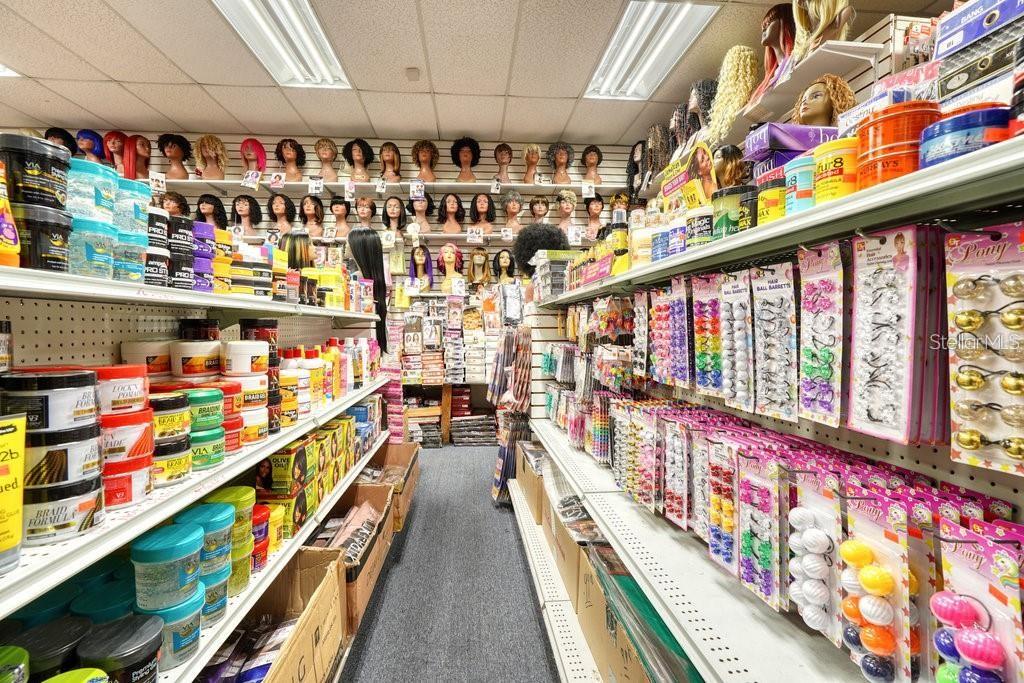 This retail store aisle features shelves stocked with hair care products and mannequin heads — 3410 NE JACKSONVILLE ROAD, OCALA, FL
