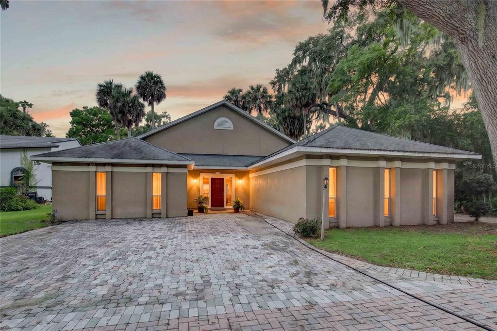 A single-story house with a paved driveway, tan stucco exterior, and a red front door — 5616 TRIMBLE PARK ROAD, MOUNT DORA, FL