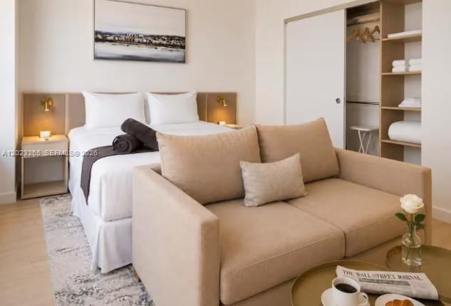A bedroom featuring a bed, a beige sofa, and an open closet with shelving — 225 N Miami Ave # 2008, Miami FL 33128, MIAMI, FL