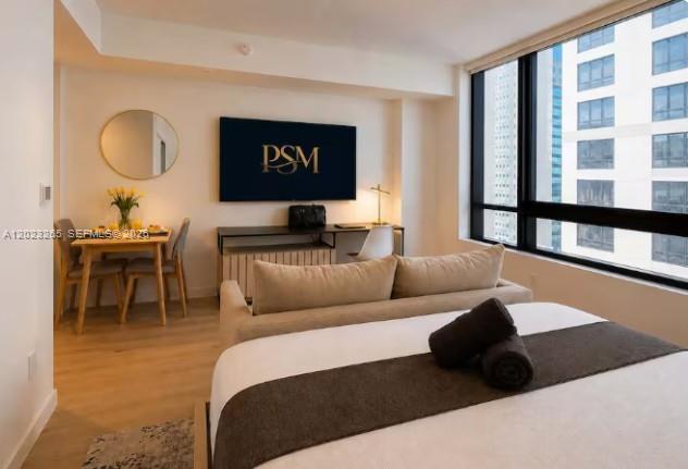 A studio apartment featuring a bed, a dining table, and a desk facing a television — 225 N Miami Ave # 2008, Miami FL 33128, MIAMI, FL
