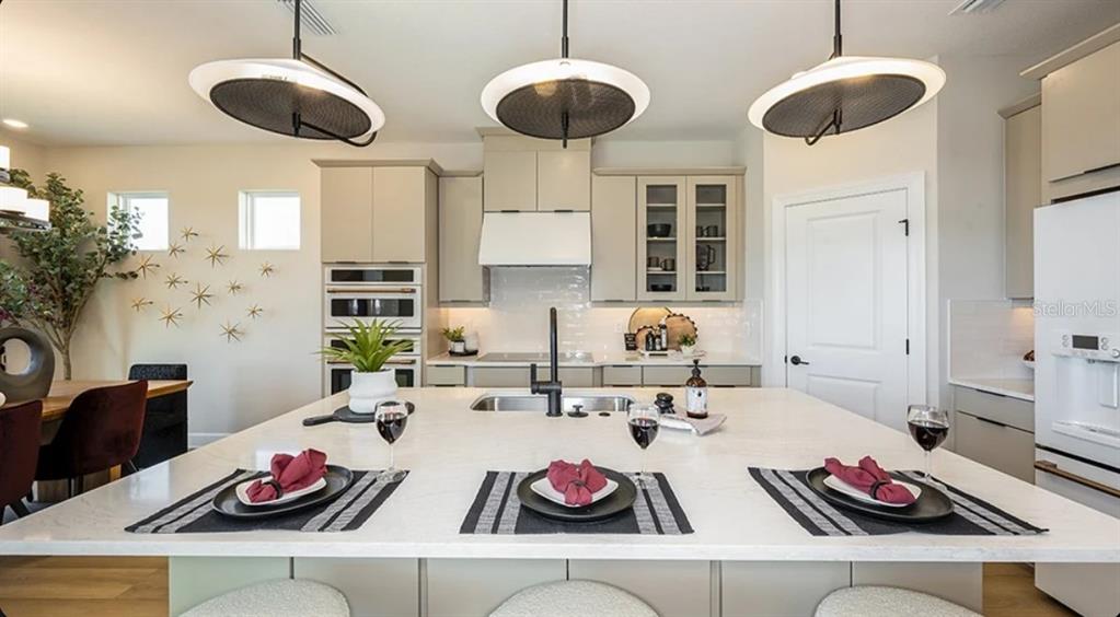 A kitchen features a large white island, pendant lighting, and light-colored cabinetry — 26201 ATRANI DRIVE, ENGLEWOOD, FL