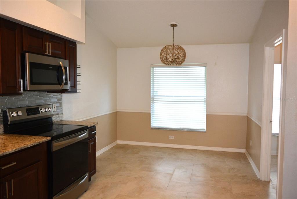 A kitchen with dark wood cabinets, stainless steel appliances, and a dining area with tile — 14648 CORKWOOD DRIVE, TAMPA, FL