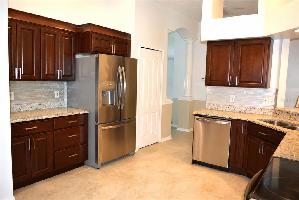 A kitchen with dark wood cabinets, stainless steel appliances, and granite countertops — 14648 CORKWOOD DRIVE, TAMPA, FL