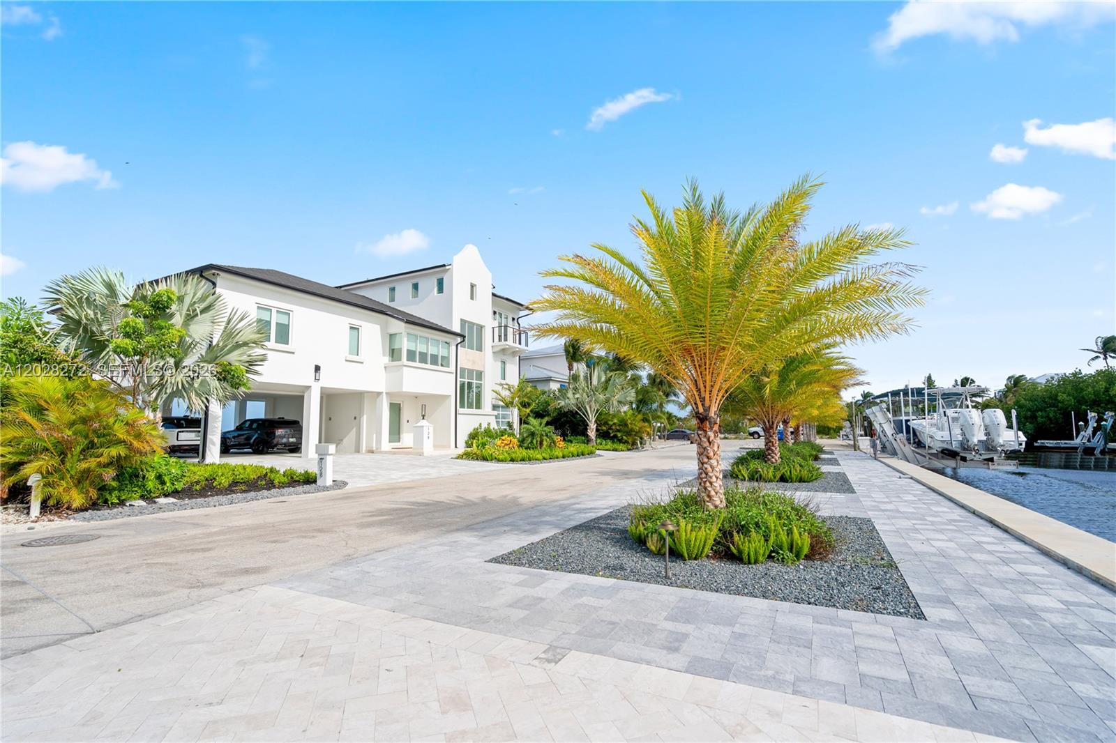 A modern white house with a covered parking area sits beside a canal with boats — 128 Sunrise Drive, Marathon FL 33050, MARATHON, FL