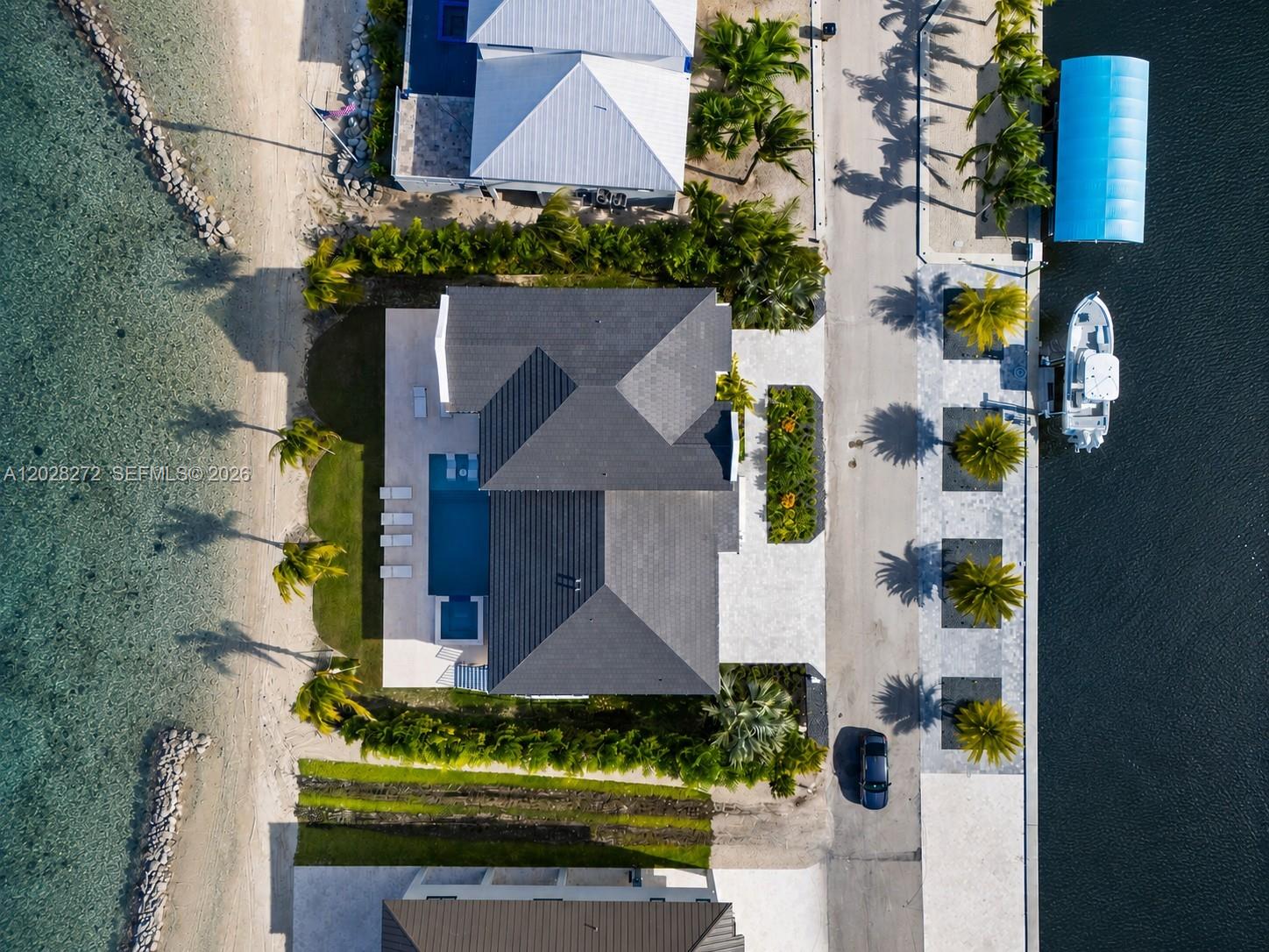 Aerial view of a waterfront house with a swimming pool, boat dock, and palm trees — 128 Sunrise Drive, Marathon FL 33050, MARATHON, FL