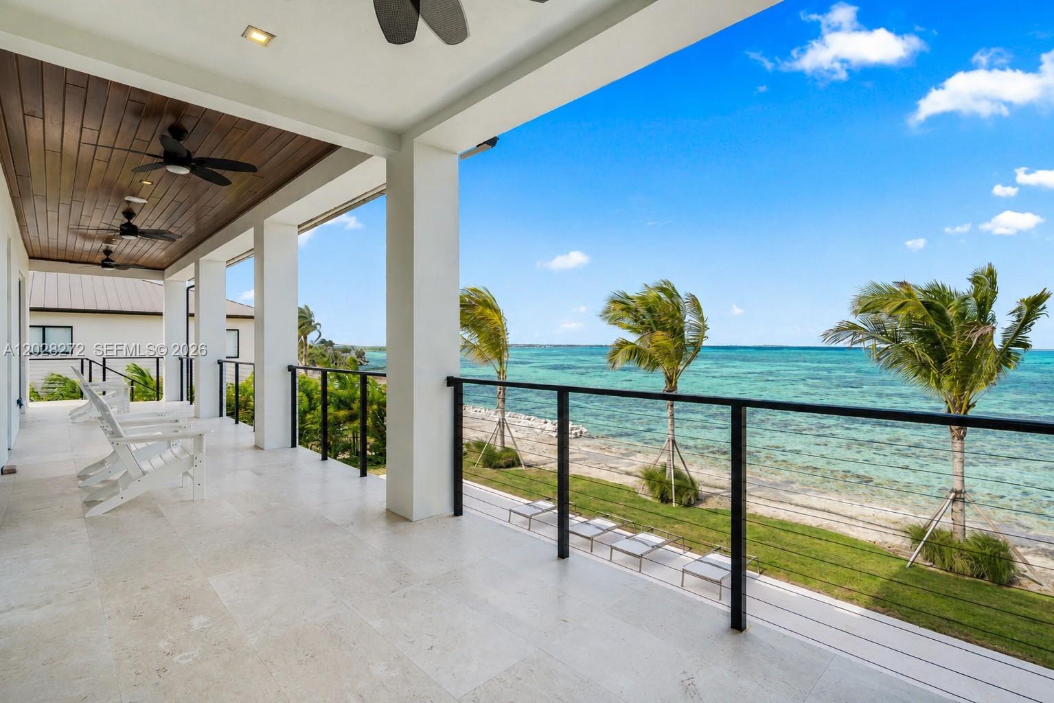 A covered balcony with white tile floors overlooks a beach and the ocean — 128 Sunrise Drive, Marathon FL 33050, MARATHON, FL