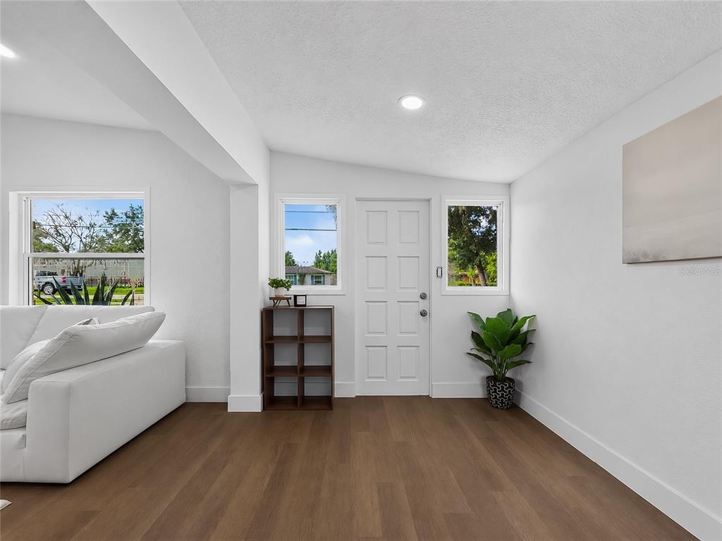 A bright entryway features white walls, wood-look flooring, a white front door, and windows — 3911 LAKE MARGARET DRIVE, ORLANDO, FL