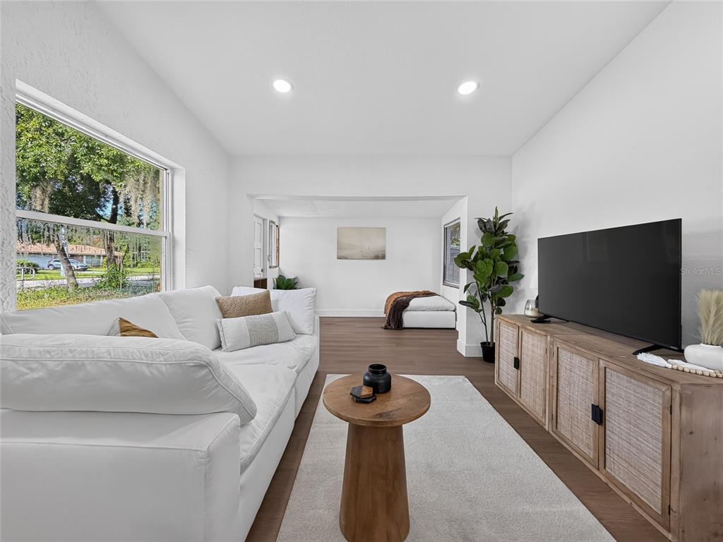 A living room features a white sofa, wood coffee table, media console, and wood flooring — 3911 LAKE MARGARET DRIVE, ORLANDO, FL