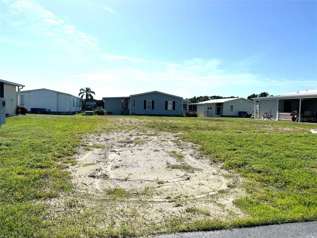 A vacant residential lot with sparse grass and sandy patches sits between two manufactured homes — 707 BLANCA, NORTH PORT, FL
