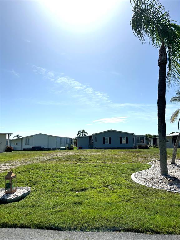 A grassy lot sits in front of two manufactured homes under a bright, sunny sky — 707 BLANCA, NORTH PORT, FL